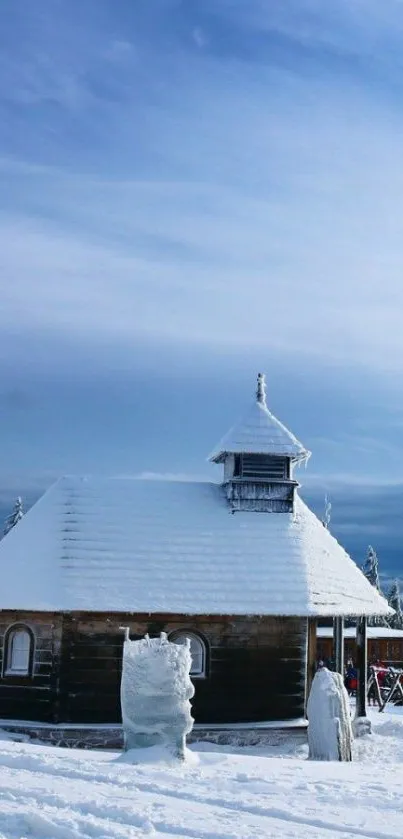 Snow-covered cabin in a serene winter landscape with a clear blue sky.