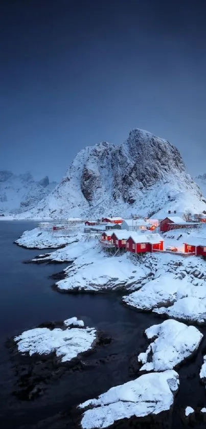 Snowy coastal village with red cabins at twilight, mountains in the background.