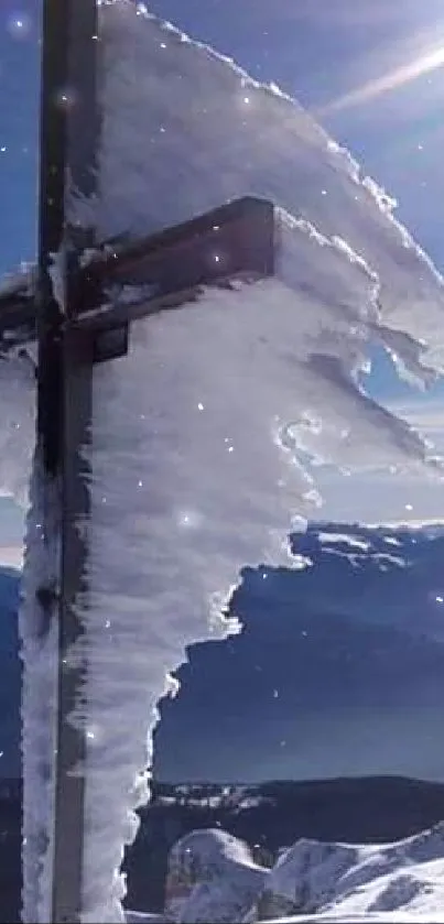 Icy cross on mountain peak with sunlit sky.