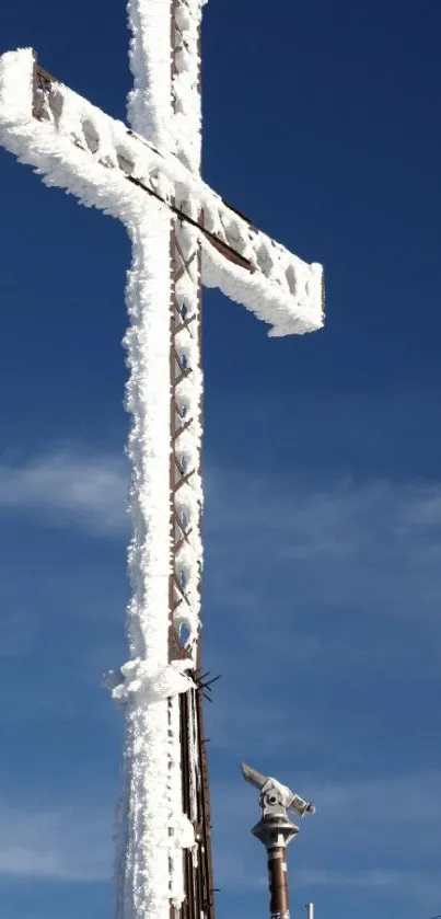 Snow-covered cross against a blue sky.