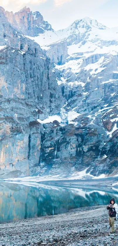 Snowy mountain landscape with lake reflection and hiker.