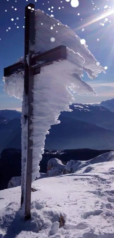 Snowy mountain peak with cross under bright blue sky.