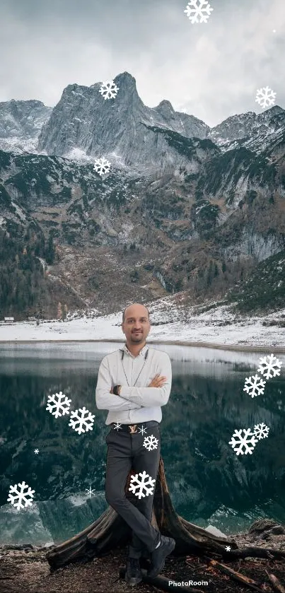 Man standing by mountain lake with snowflakes falling.