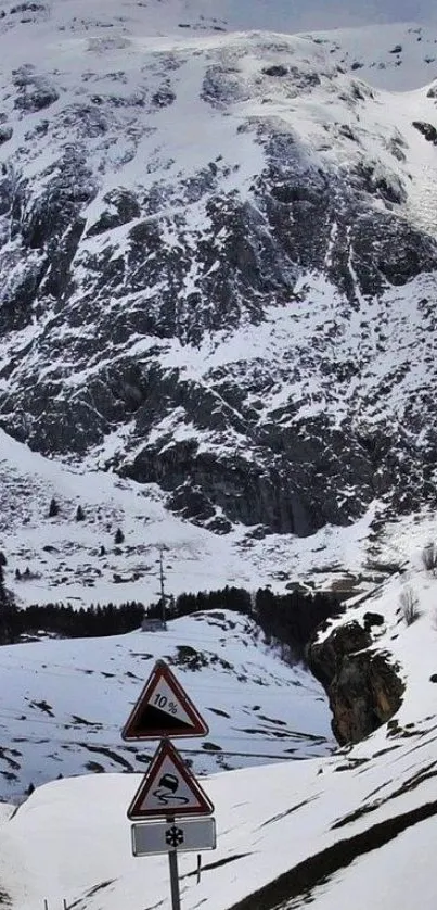 Snowy mountain road with warning signs in winter landscape.