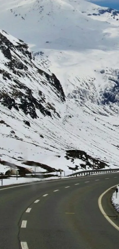 Snowy mountain road winding through winter landscape.