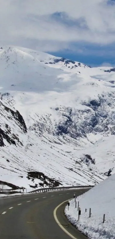 Scenic snowy mountain road under a clear blue sky with rugged peaks.