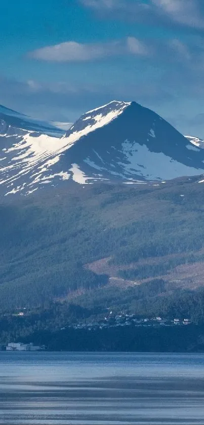 Majestic snowy mountain with serene water reflection and lush greenery.