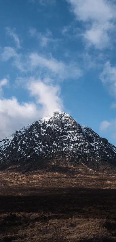 Snowy mountain under a blue sky with clouds.