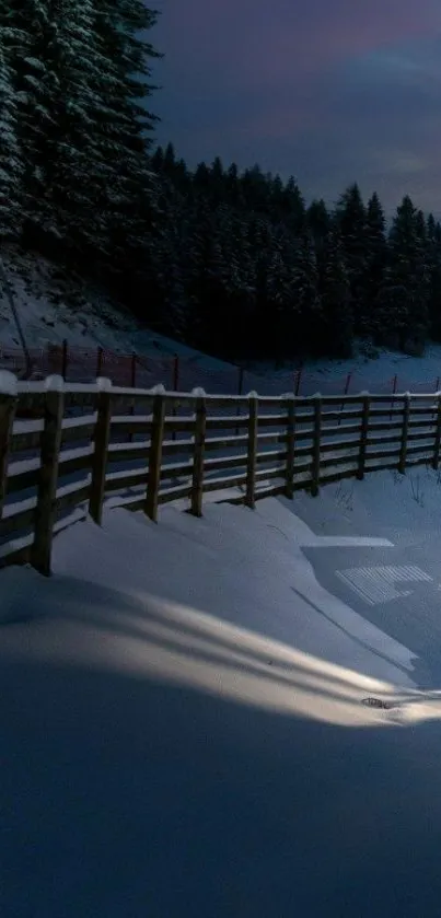 Serene snowy evening with forest and fence under a dark blue night sky.