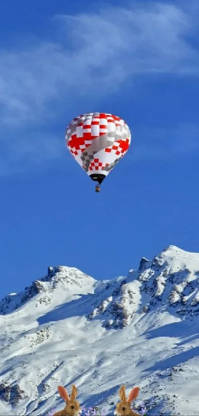 Hot air balloon over snowy mountains with blue sky.