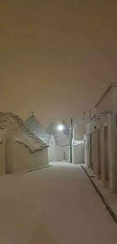 Snow-covered street with trullo roofs and warm gray sky at night.