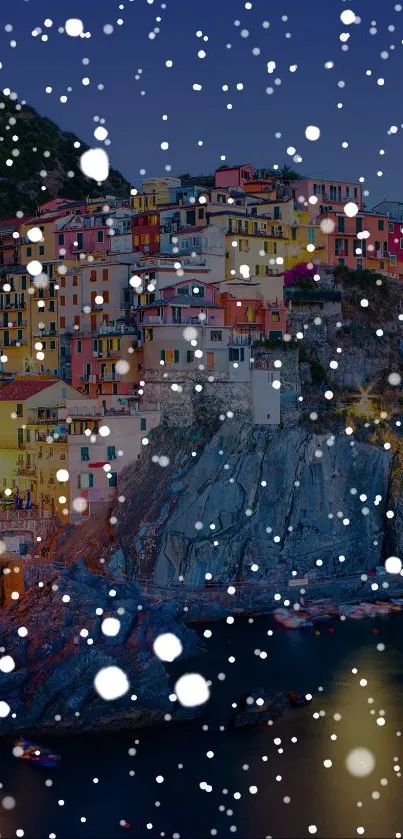 Colorful village at night with snowfall on a cliffside, perfect for mobile wallpaper.