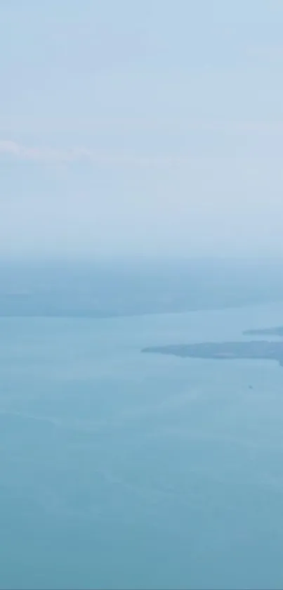 A lone bird flying over a calm, expansive sea beneath a serene sky.