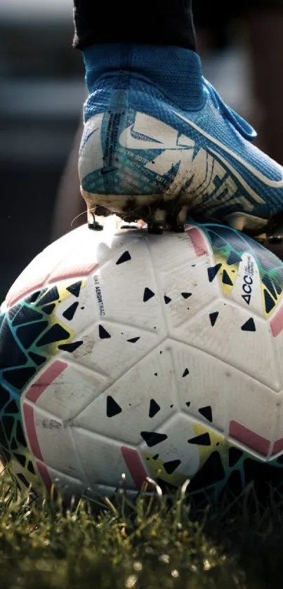 Blue cleats resting on a soccer ball on grass.