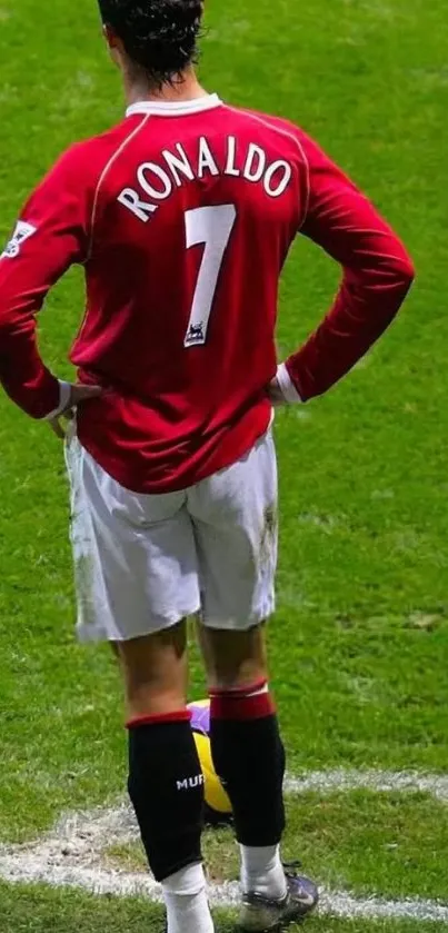 Soccer player stands by the corner flag on a grassy field.