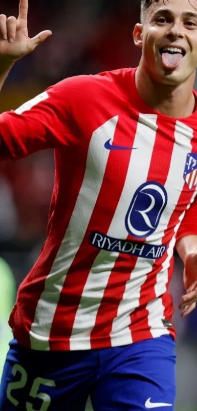 Soccer player in red and white jersey celebrating on the field.