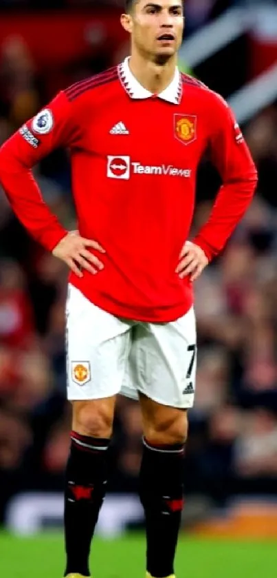 Soccer player in red jersey standing on a football field.