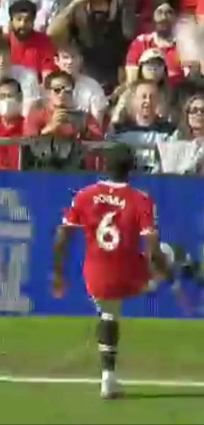 Footballer in red jersey mid-action on the field, exciting crowd in the background.