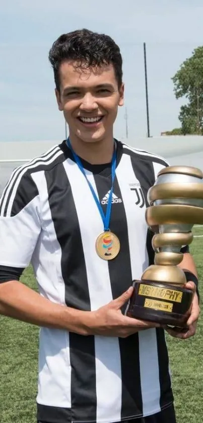 Smiling athlete holding trophy on soccer field wallpaper.