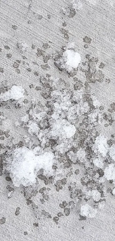 White snow scattered on textured gray concrete surface.