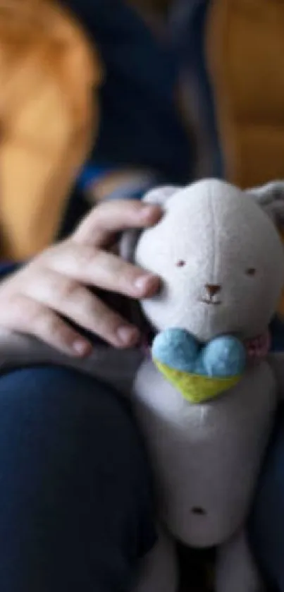 Child holds plush bunny on lap, wearing cozy outfit.