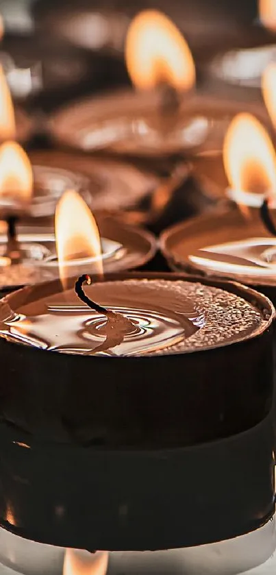 Warm candlelight with flickering flames creates a serene and calming mobile wallpaper.