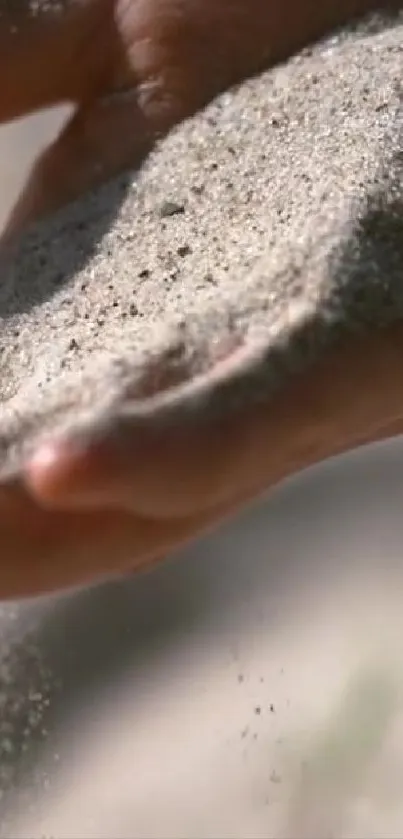 Hand holding flowing sand in a serene setting.