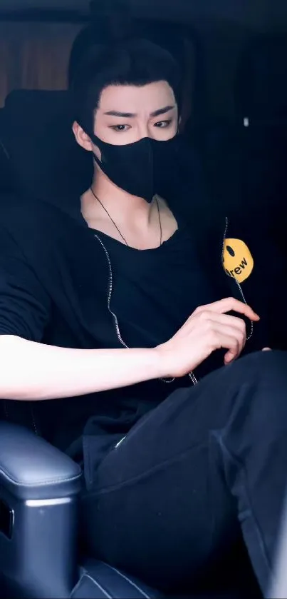 A young man in a black mask sitting in a car, exuding a stylish urban vibe.