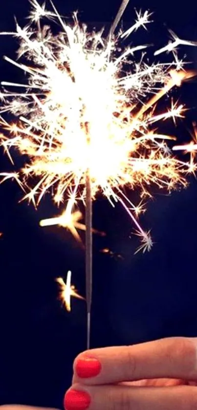 Sparkler in hand with dark blue background, festive glow.