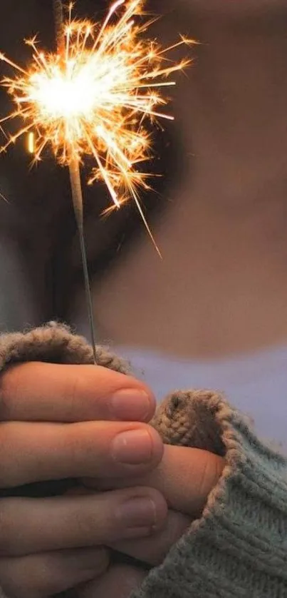 Hand holding sparkler with cozy glow in soft background.