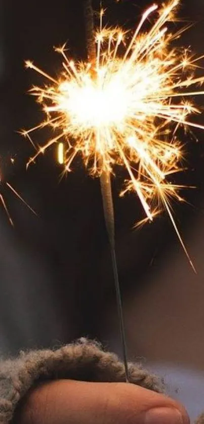 A warm orange sparkler glowing brightly in a person's hand.