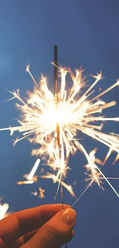 Vibrant sparkler glowing against a soft blue sky background.