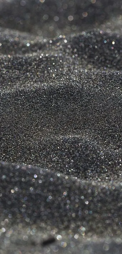 Close-up of sparkling black sand texture with dark tones.