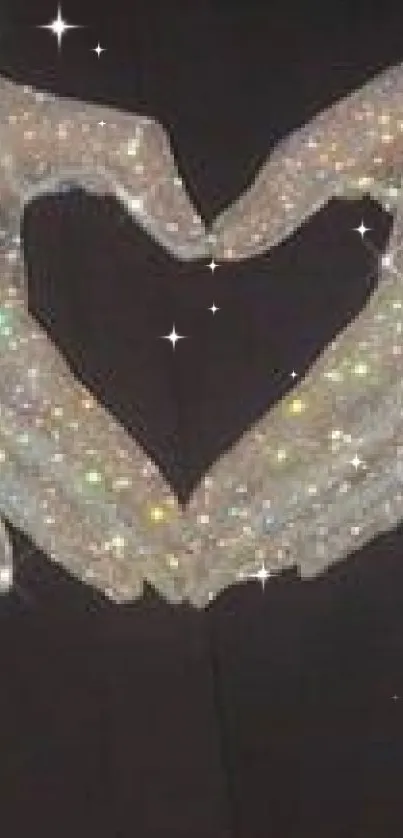 Glittering gloves forming a heart shape against a dark background.