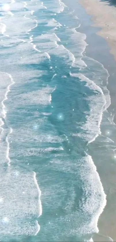 Aerial view of sparkling ocean waves along sandy shore.