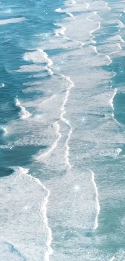 Aerial view of sparkling ocean waves in shades of blue and white foam.