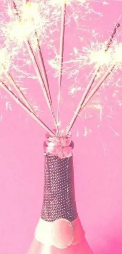 Pink champagne bottle with sparklers on a festive pink background.