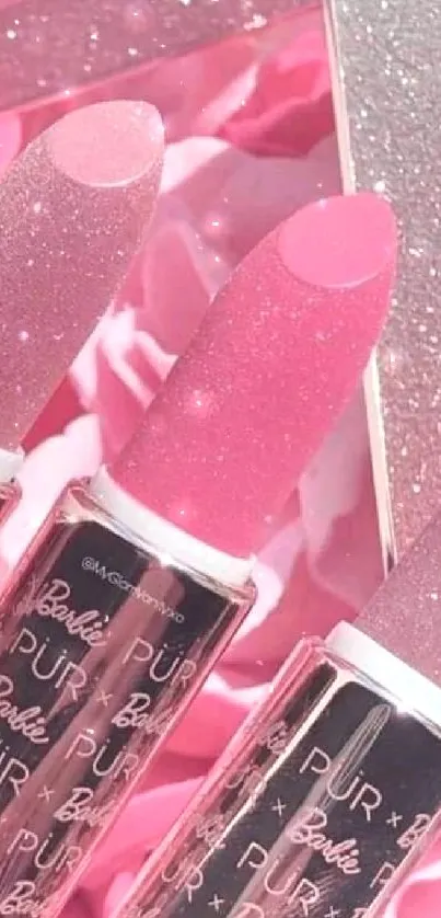 Vibrant pink lipsticks with glitter accents on a mobile wallpaper.