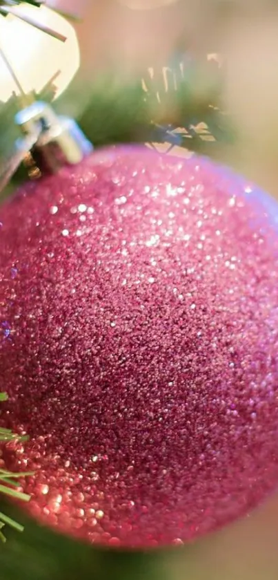 Close-up of a sparkling pink Christmas ornament on a tree.