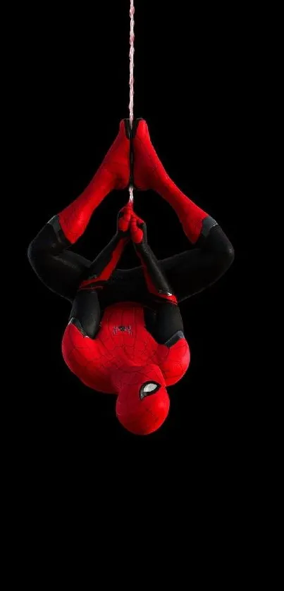 Superhero hanging upside down on a black background wallpaper.