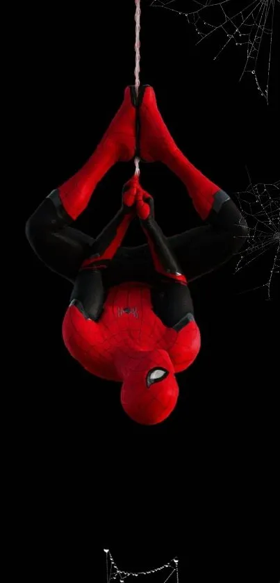 Spider-Man hanging upside down on a web with black background.