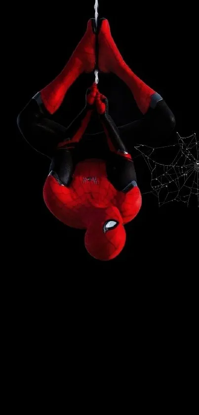 Spiderman hanging on web against dark background.