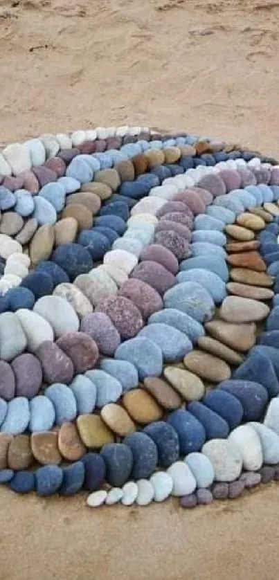 Circular spiral of colorful stones on sandy beach.