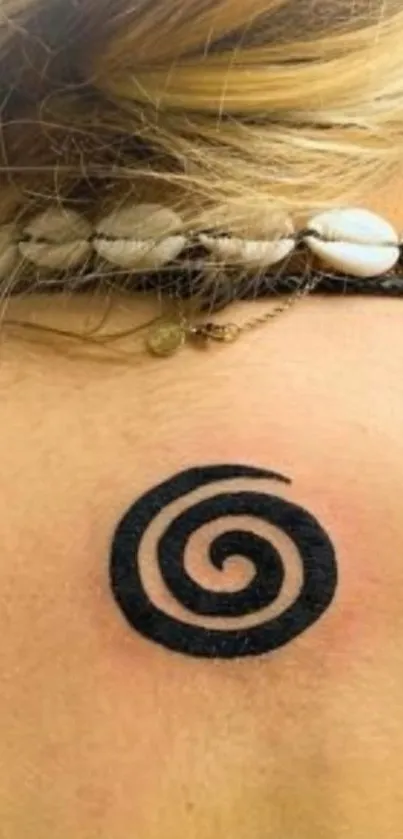 Spiral tattoo on shoulder with a beige background.