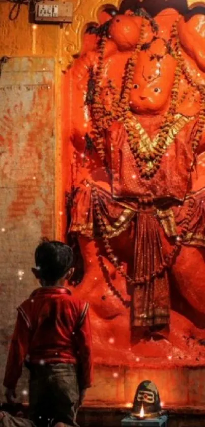 Child kneeling in prayer before an orange statue in a serene setting.