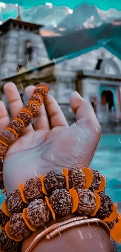 Hand reaching towards a temple with mountains in the background.