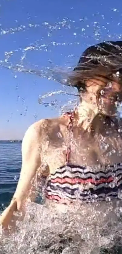 Woman splashing in the ocean under a clear blue sky.