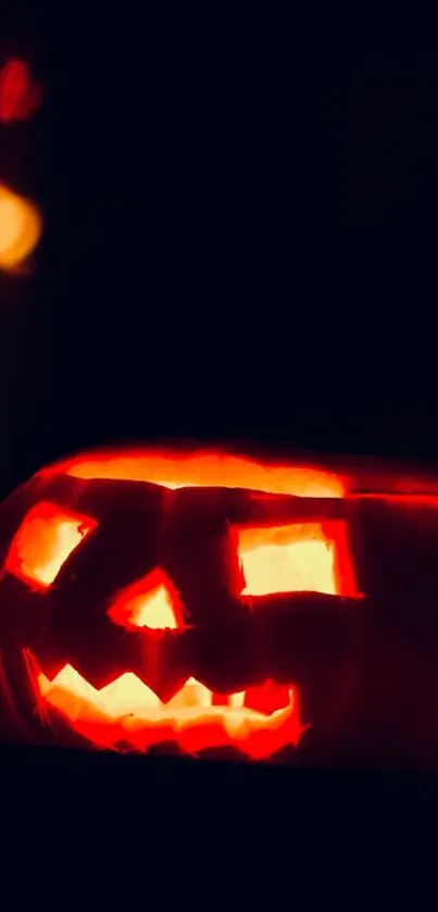 Glowing carved pumpkin on dark background.