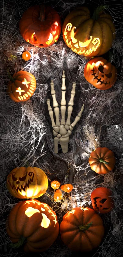 Spooky Halloween wallpaper with pumpkins, cobwebs, and a skeleton hand.