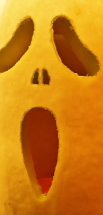 Eerie pumpkin carving wallpaper with ghostly face on phone display.